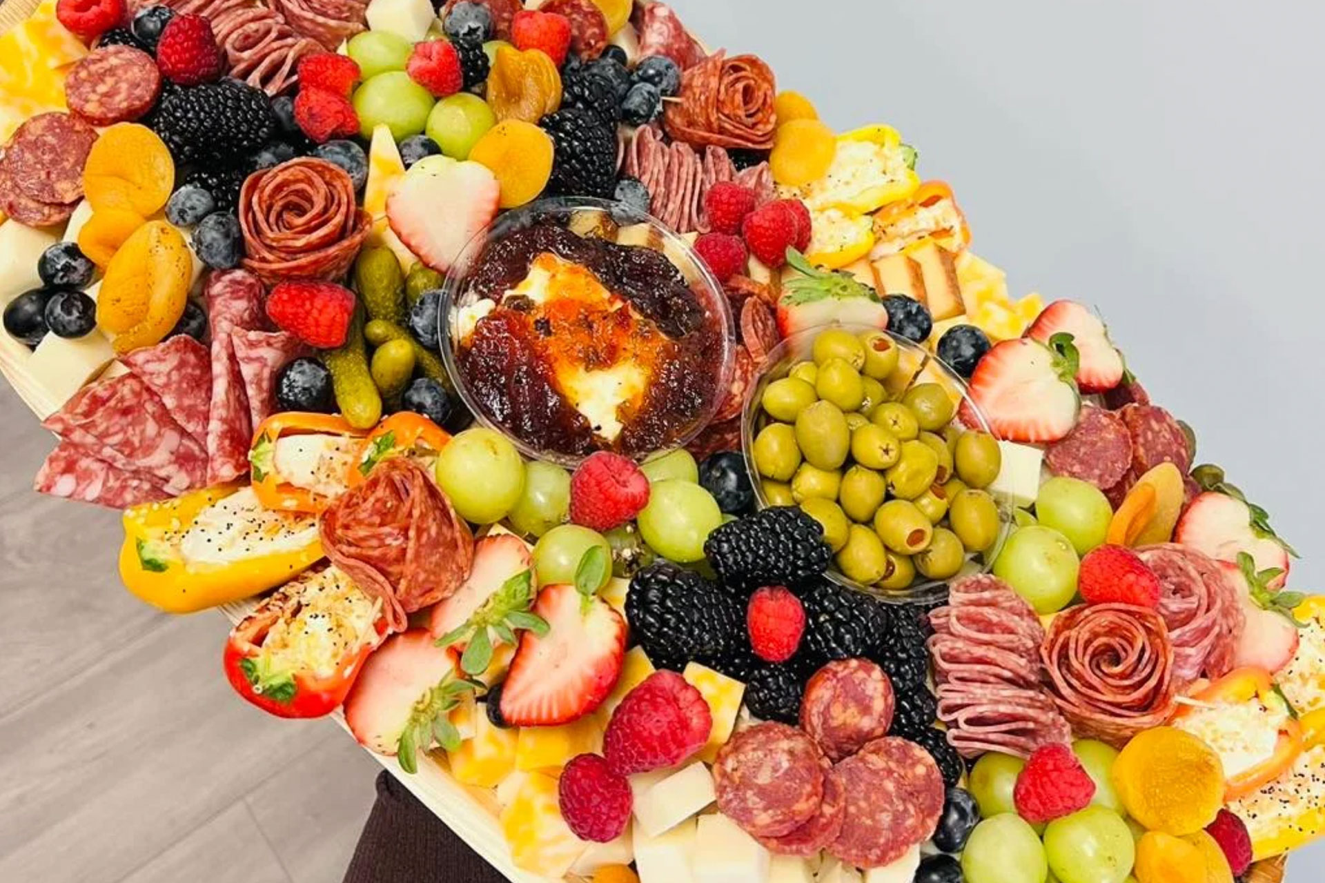 A colorful charcuterie board with fruits, cheeses, olives, and meats.
